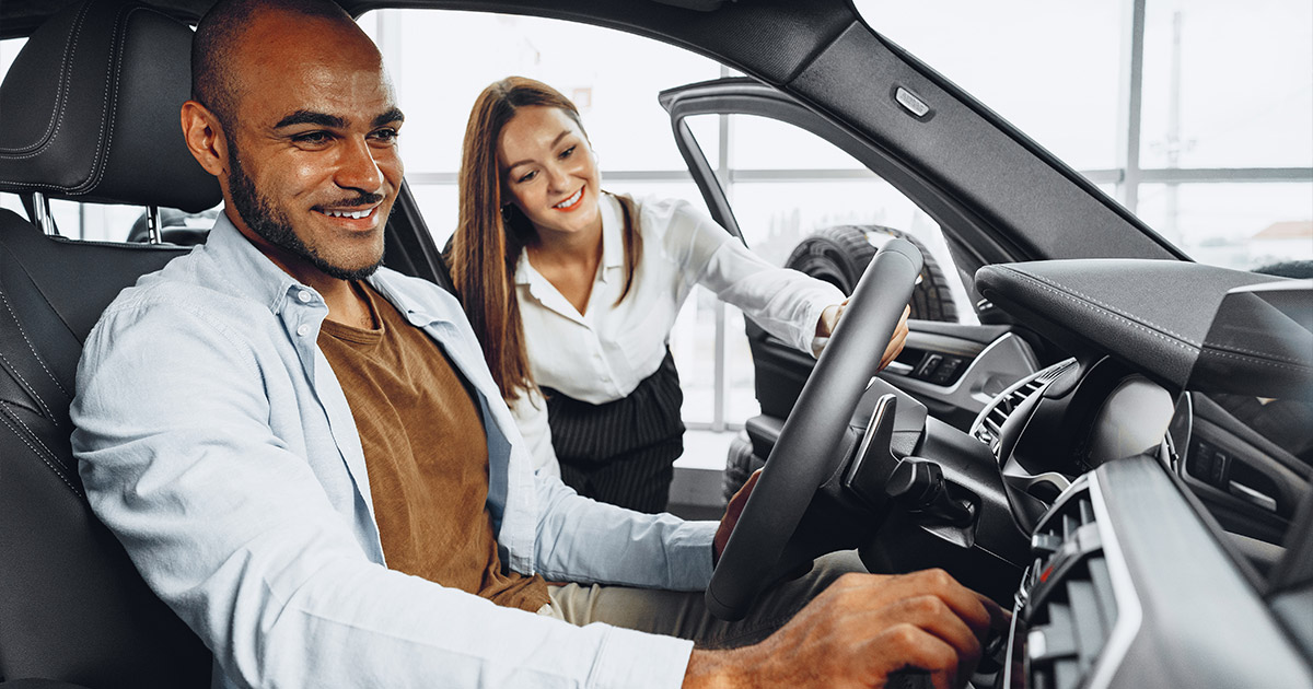 Happy car buyer sitting in new vehicle with smiling saleswoman at Beck Motors Sunnyside dealership, test driving Chevrolet sedan interior.