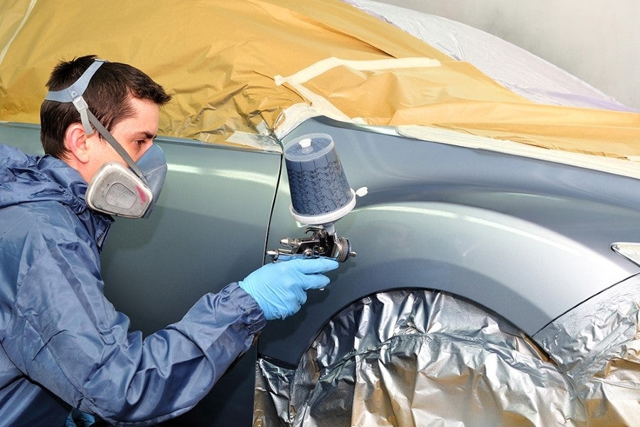 Technician painting a car at the service center