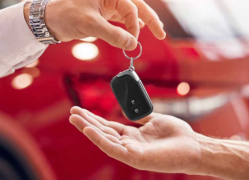 person’s hand handing over a car key to another person’s open hand